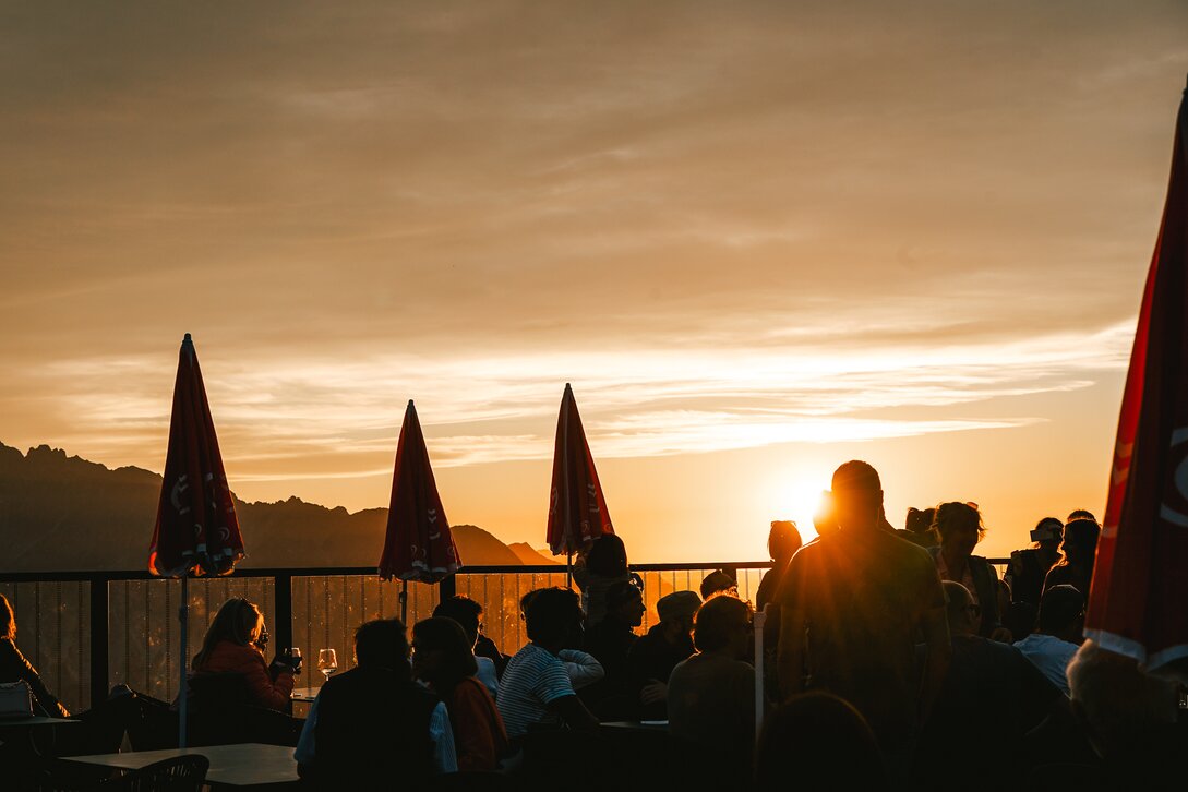Sonnenuntergang beim Sundowner am Kapell der Silvretta Montafon mit Konturen von Menschen im Vordergrund | © Silvretta Montafon - Vanessa Strauch