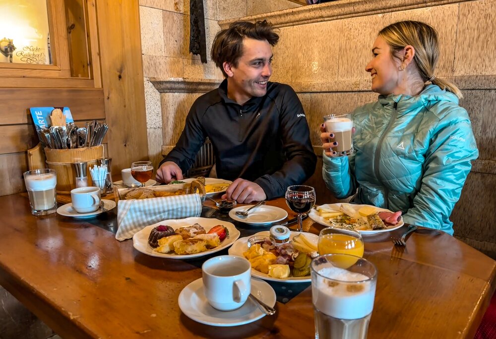 Ein Pärchen sitzt beim Bergfrühstück bei gedecktem Tisch in einer Berghütte. | © Vanessa Strauch - Silvretta Montafon