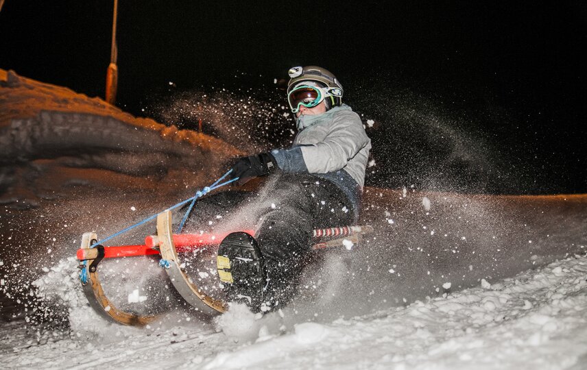 Eine Person beim Nachtrodeln im Schnee. | © Silvretta Montafon - Marcel Mehrling