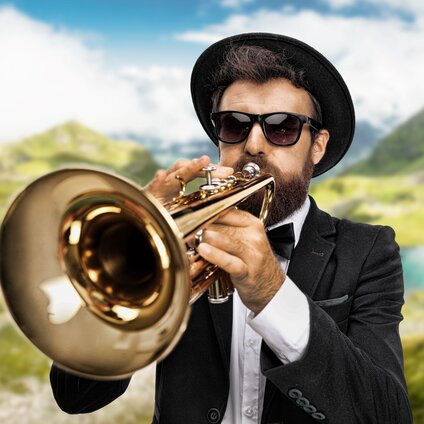Ein Musiker mit und und Sonnenbrille spielt auf einer Trompete in der Silvretta Montafon.  | © Silvretta Montafon