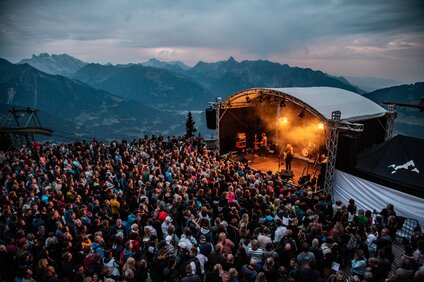 Ein Konzert beim Sonnenuntergang mit bunter Beleuchtung und großem Publikum | © Silvretta Montafon - Frederike Weber