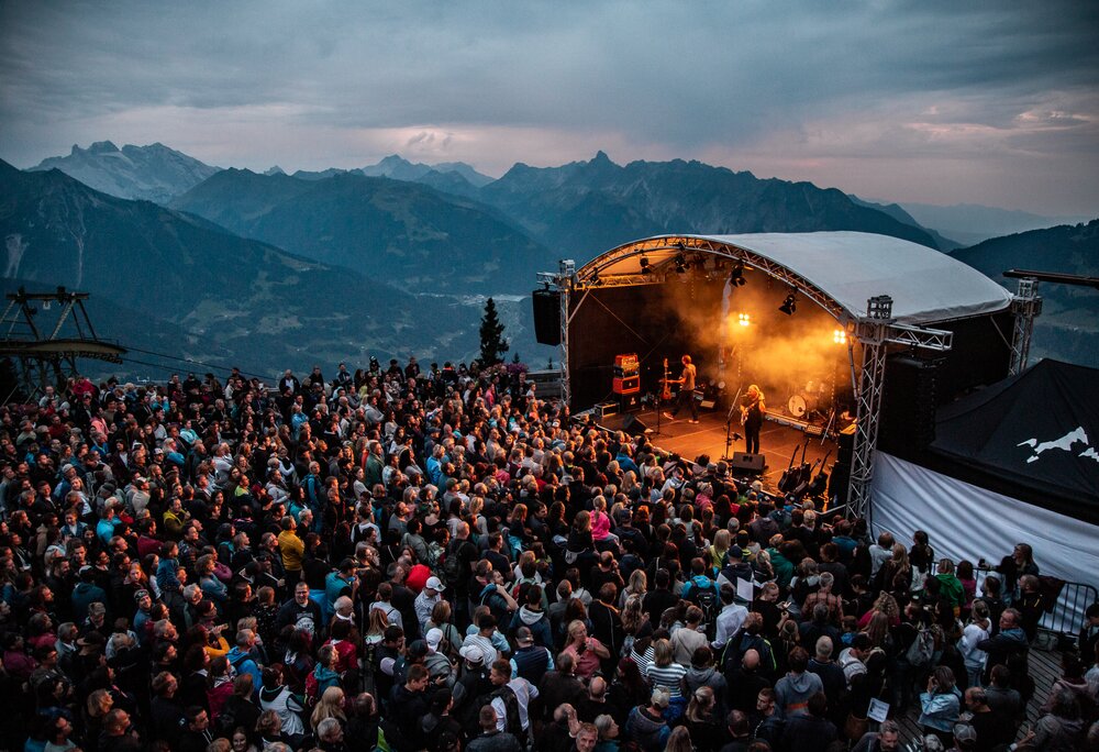 Ein Konzert beim Sonnenuntergang mit bunter Beleuchtung und großem Publikum | © Silvretta Montafon - Frederike Weber