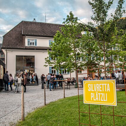 Ein "Silvretta Platzli" Schild mit Gastgarten im Hintergrund. | © Silvretta Montafon - Friederike Weber