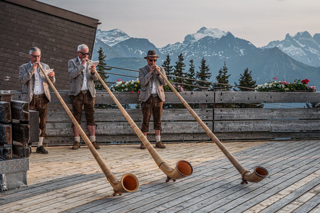 Drei Alphorngläser spielen auf einer Terrasse in den Bergen der Silvretta MOntafon. | © Silvretta Montafon - Vanessa Strauch