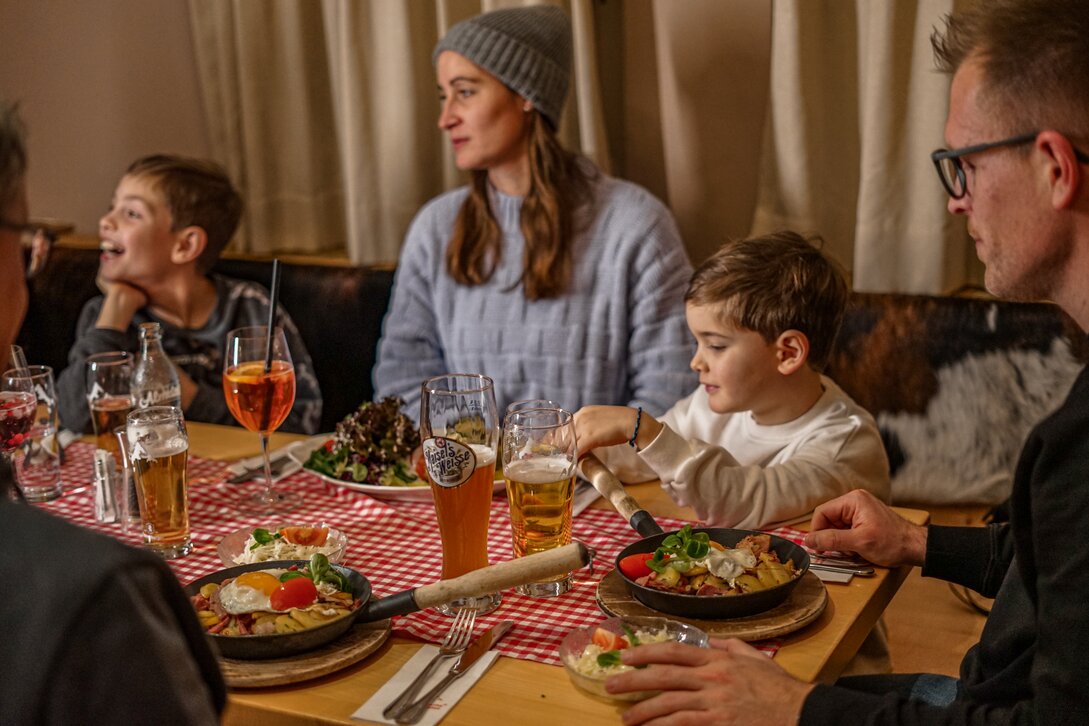 Eine Gruppe von Personen am gedeckten Tisch mit herzhaften Speisen in einer Berghütte im Skigebiet Silvretta Montafon. | © Vanessa Strauch - Silvretta Montafon