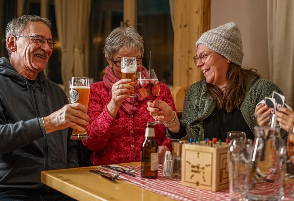 Drei Personen stoßen in einer gemütlichen Berghütte an. | © Vanessa Strauch - Silvretta Montafon