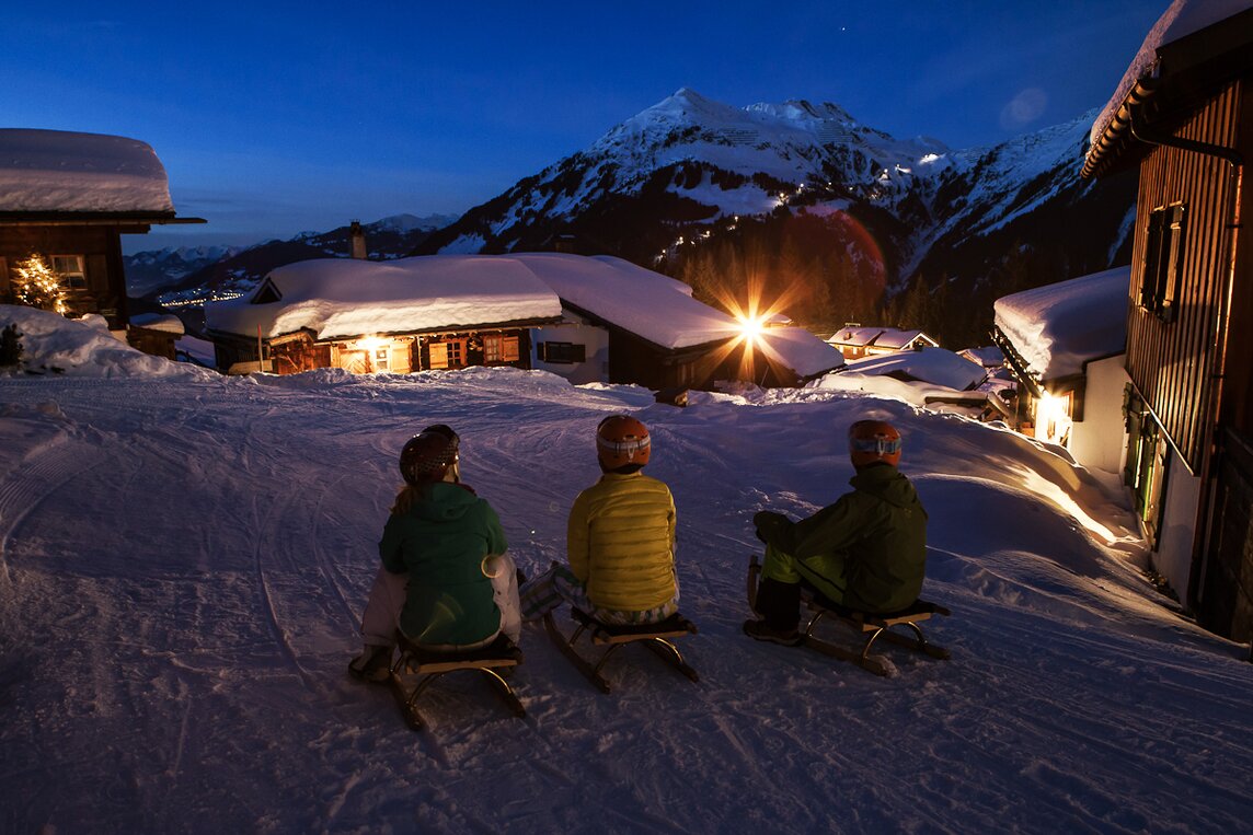 Drei Freunde auf dem Rodel vor der Abfahrt über die Nachtrodelbahn Garfrescha in der Silvretta Montafon | © Silvretta Montafon - Daniel Zangerl