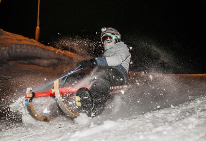 Eine Person beim Nachtrodeln im Schnee. | © Silvretta Montafon - Marcel Mehrling